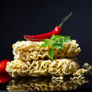 Raw instant food noodles with spices and vegetables food ingredients with copy space on dark background