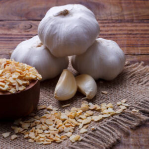 garlic cloves, bulb and flakes on old wooden board